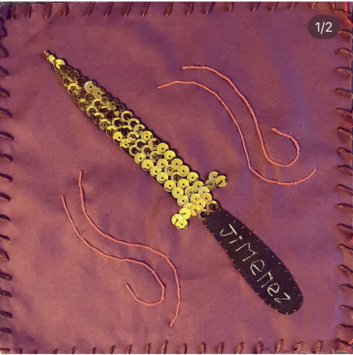 A hang embroidered flag of a gold-sequins dagger with the name Jimenez stitched on the handle.