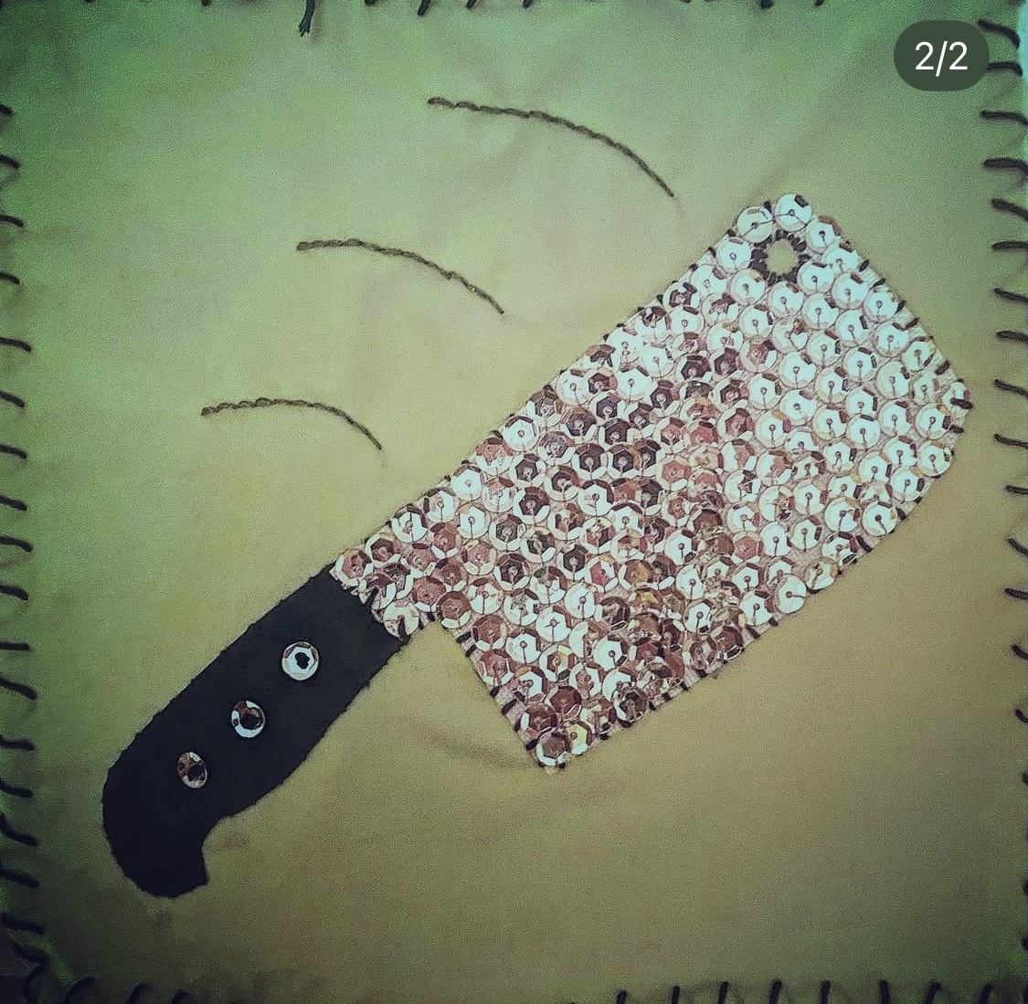 A hand embroidered flag of a silver sequins-covered cleaver with motion lines indicating a chop!