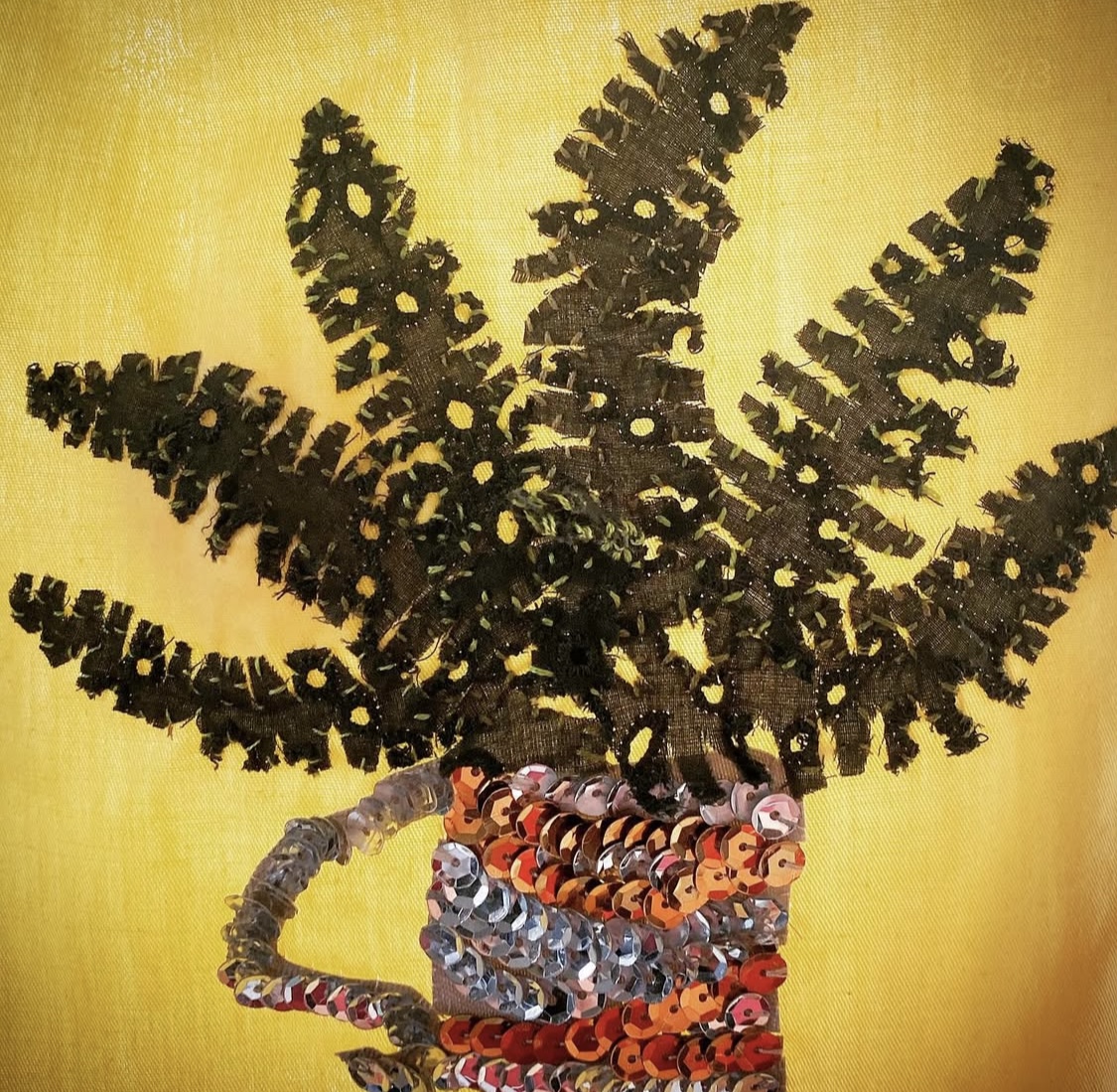 Hand embroidered flag of a fern in a sequins-sparkled mug.